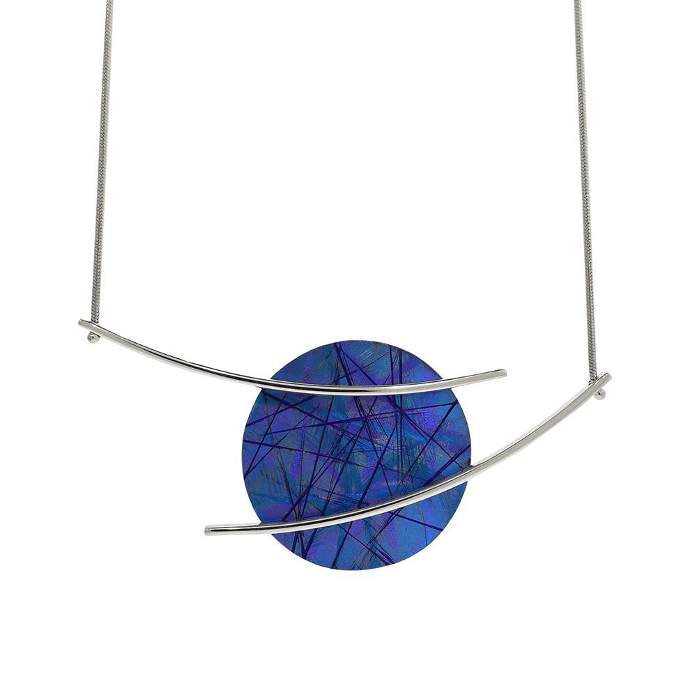 This blue titanium necklace is made from sterling silver and anodized titanium. The pendant is circle shaped and made of titanium it also has a blue color and colorful designs achieved by anodizing the metal. There are silver wires that extend past the pendant and reach across the piece.