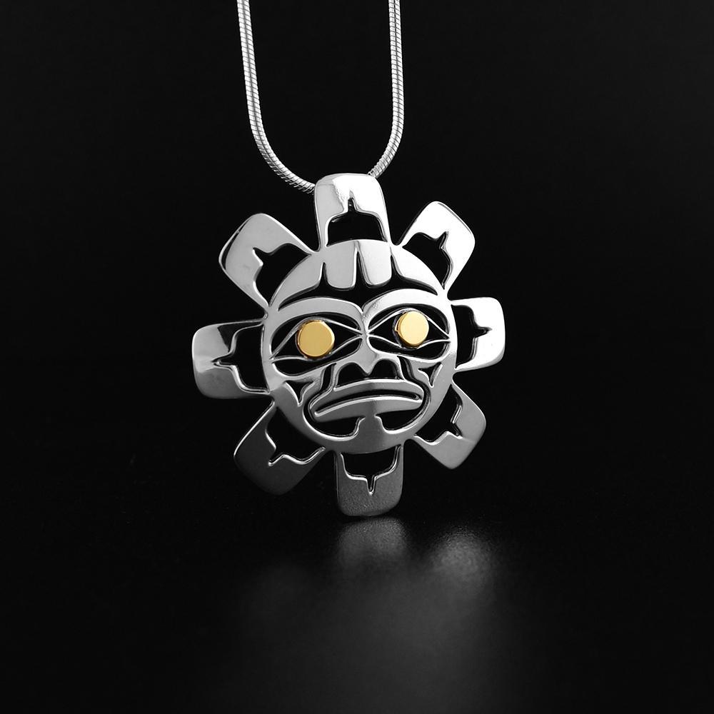 This Sun pendant is made from sterling silver and 18K gold. The pendant is shaped like and has cutouts that have been cast into it that depict the Sun. The eyes of the Sun are made from 14K gold.