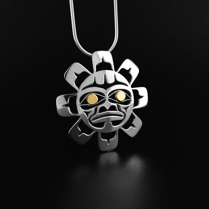 This Sun pendant is made from sterling silver and 18K gold. The pendant is shaped like and has cutouts that have been cast into it that depict the Sun. The eyes of the Sun are made from 14K gold.