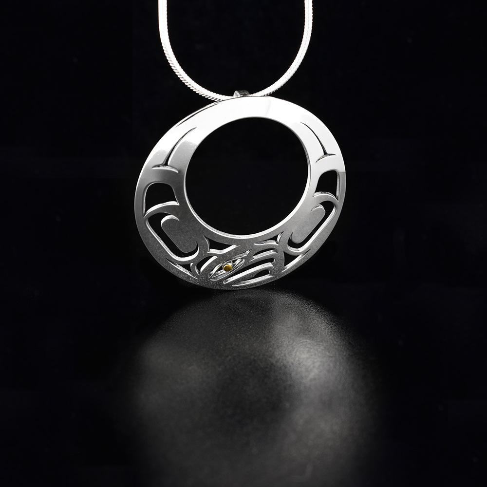 This Eagle pendant is made from sterling silver and 18K gold with a large, circle shape with a circle cutout in the middle. There are also cutout designs in the pendant that depict the Eagle; the eye of the Eagle is made form 18K gold.