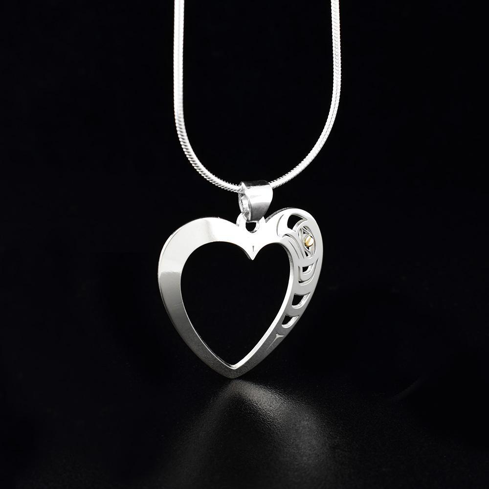These sterling silver heart pendant necklace has a heart shaped cutout in the middle of it. There are cutout designs in the surface of the pendant that depicts the Eagle and its eye is made from 18K gold.