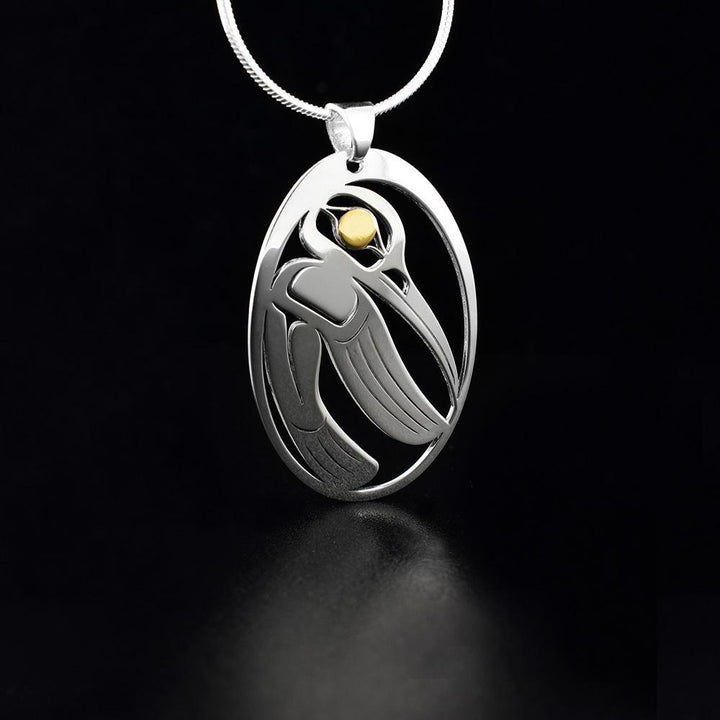 This cutout Hummingbird pendant is made from sterling silver and 18K gold with an oval shape. There are cutout designs in the pendant that depict the Hummingbird and the eyes of it are made from gold.