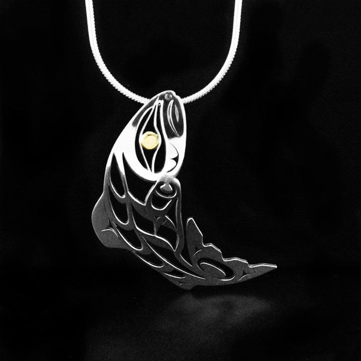 This sterling silver and 18K gold fish pendant is shaped like has cutouts in it that depict the Salmon.