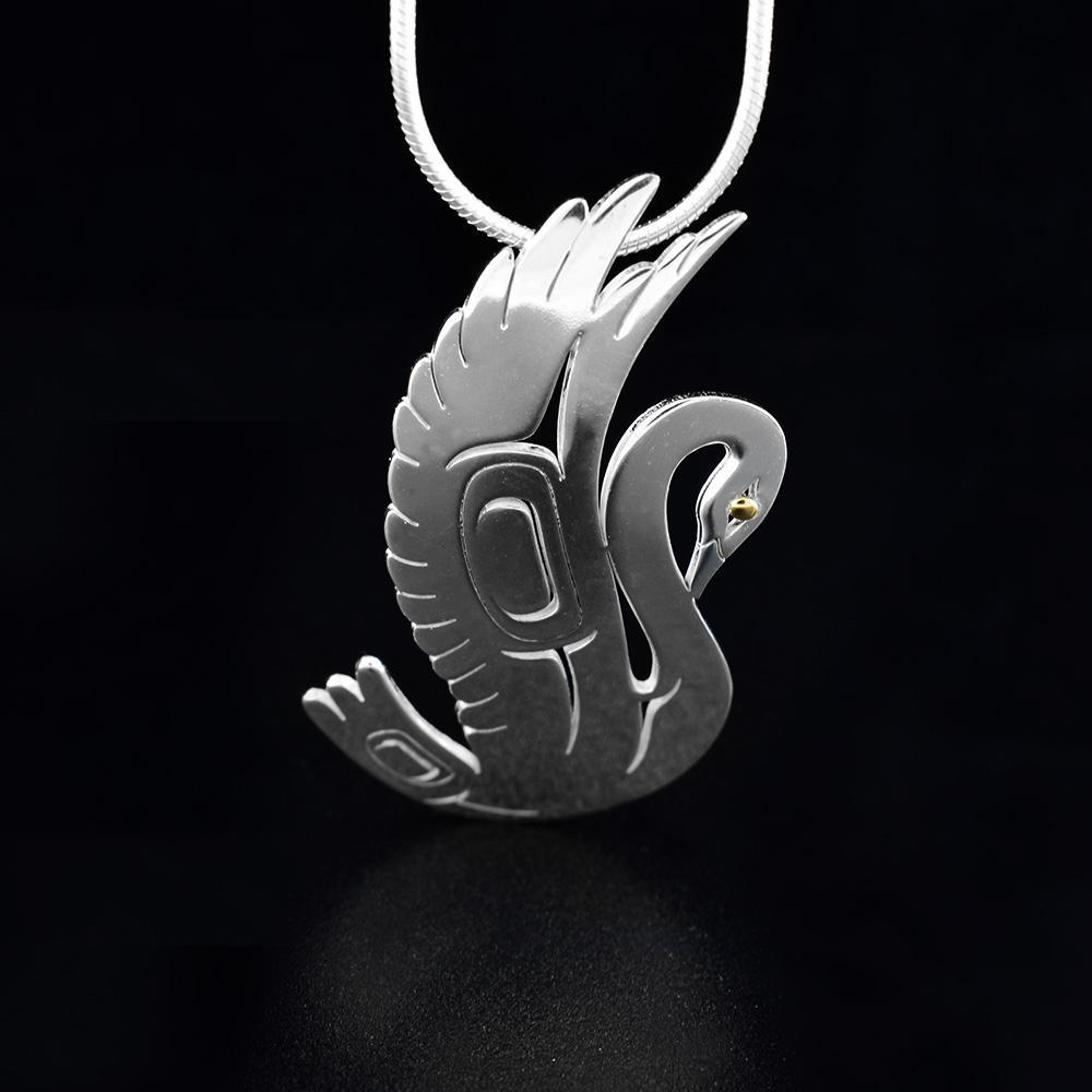 This Swan pendant is made from sterling silver and 18K gold and is shaped like the Swan. There are carvings on the surface of the pendant that depict the Swan and its eyes are made from gold.
