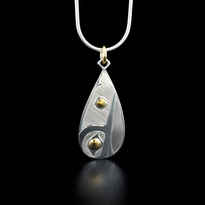 This Sterling Silver and 14k Gold Teardrop Hummingbird Pendant with a 10k gold bail was hand carved by Haisla artist Hollie Bartlett.  The pendant depicts the face of a hummingbird, with both the eye of the hummingbird and the embellishment being made of 14K gold.  The pendant measures 1.5" x 0.6", including the gold bail.  The chain is not included. The Hummingbird Legend Represents: BEAUTY, LOVE, HARMONY.