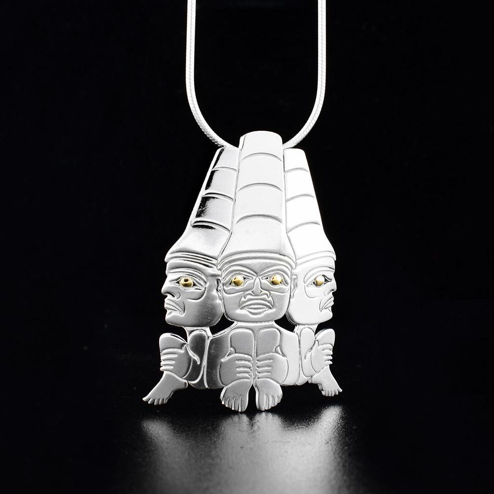 This large silver pendant is made from sterling silver and 18K gold. The piece is shaped like and has cutouts that depict three watchmen with golden eyes. The watchmen are positioned facing outward in a circle.