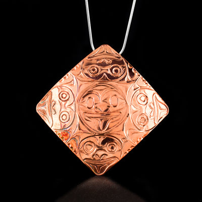 Square Copper Frog Pendant by Paddy Seaweed. The design depicts 5 frogs in total: one frog in the center of the pendant right-way forward, one frog underneath, one from to the right facing the right, one from to the left facing the left, and one frog at the top facing upward. The 4 frogs at each corner have legs and their tongue sticking out.