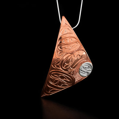 Copper Eagle and Orca Triangle Pendant by Paddy Seaweed. The design depicts the head of an eagle, made from copper, with two large wings. In the right corner of the pendant is the face of an orca, made from sterling silver, facing the eagle.