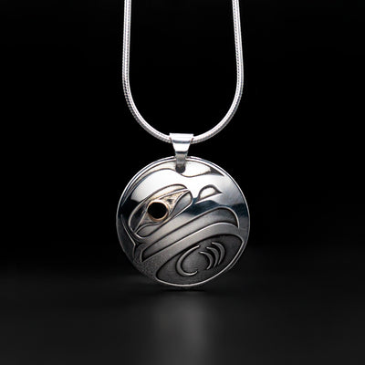 This Sterling Silver and 18K Gold Round Eagle Pendant was created by Tahltan artist, Grant Pauls. He has used sterling silver to create the pendant along with 18K Gold in the raven's eye.  The pendant is 1.0" in diameter.  The chain is not included. The Eagle Legend Represents: POWER, INTELLIGENCE, VISION.