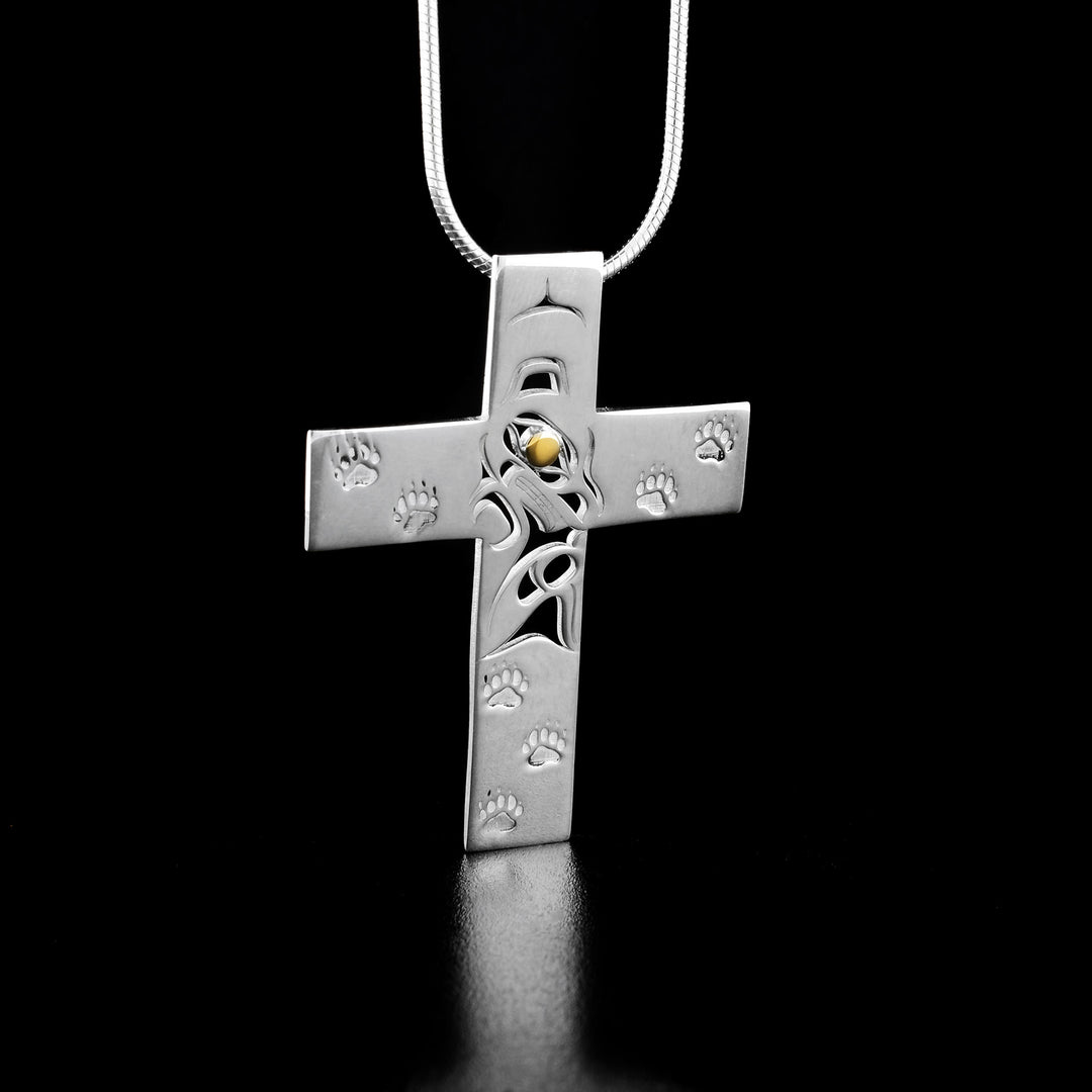 This gold and silver cross pendant is made from sterling silver and 18K gold. The pendant is shaped like a cross and there is a cutout design of the Bear in the middle of it. The eye of the Bear is made from 18K gold.