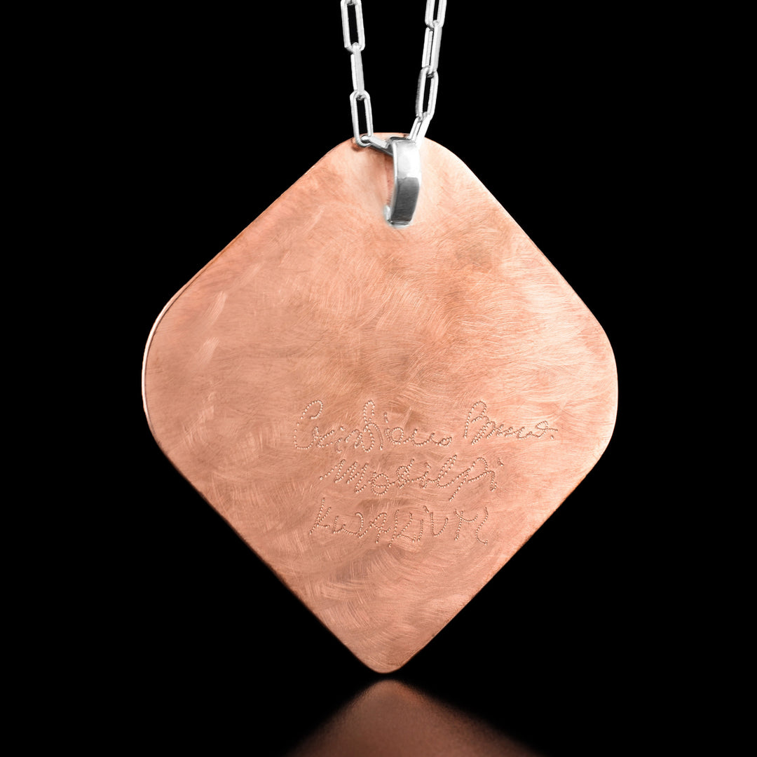 The back of the pendant is purely copper with the artists name carved into it.