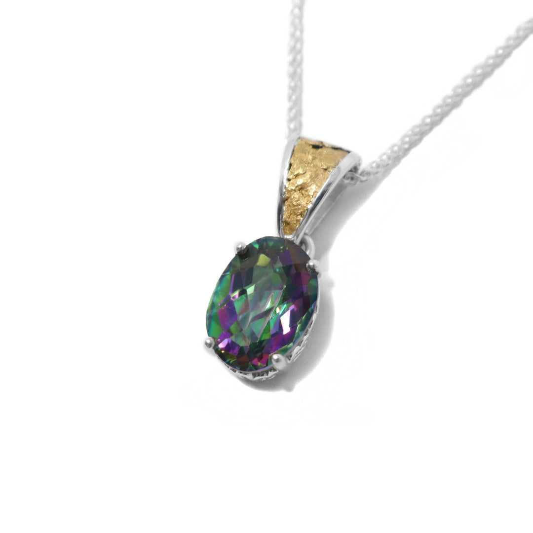 This blue topaz gold pendant is in the shape of an oval and has the colours green, purple, blue, and pink. The topaz is held in place by a sterling silver claw setting. The attached bail has 22k yellow gold nuggets on the front.