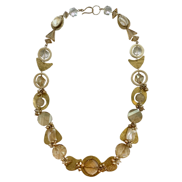 This unique pearl and crystal necklace is made from hand worked brass, Austrian crystals, freshwater pearls and glass. The necklace features many chain links and beads of different shapes and materials running along the necklace.