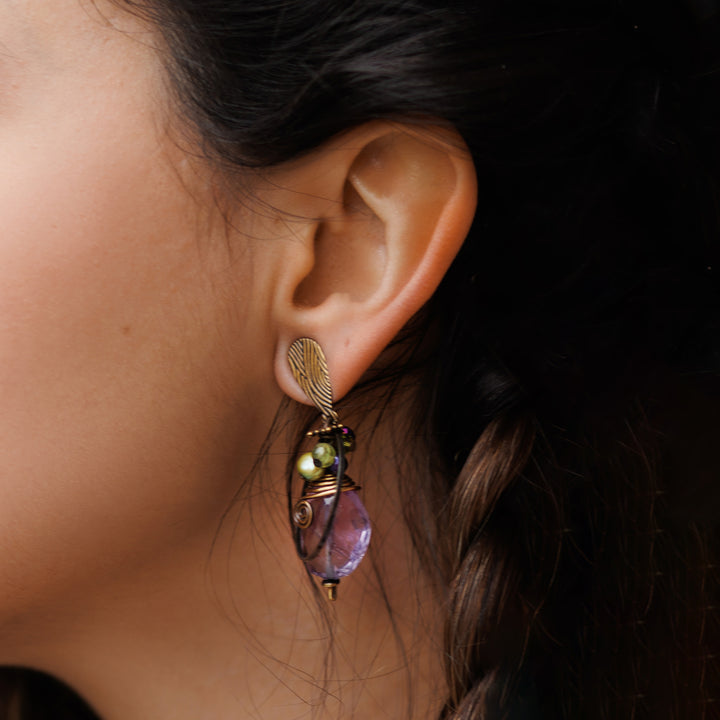 Model with olive-toned skin and brown hair wearing crystal drop earrings made with Austrian crystal, freshwater pearls, amethyst and peridot. Boho earrings are handmade in Canada and available online.