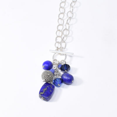 Blue Crystal and Gemstone Cluster Pendant Necklace handcrafted by artist Karley Smith. Made of sterling silver, Swarovski Crystal, sodalite and lapis lazuli. Necklace closes at front with a toggle clasp. Pendant measures 2.15" x 1" including toggle clasp and chain is 20" long.