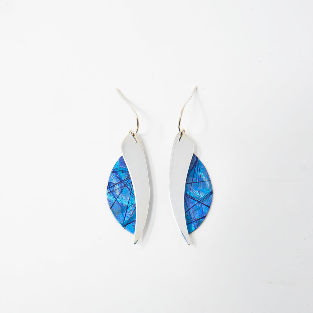 These titanium dangle earrings are made from sterling silver and anodized titanium and have a wavy, teardrop shape. The hangs are half anodized titanium with a blue color and other colorful designs on it and half shinning sterling silver.
