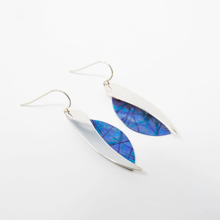 These titanium dangle earrings are made from sterling silver and anodized titanium and have a wavy, teardrop shape. The hangs are half anodized titanium with a blue color and other colorful designs on it and half shinning sterling silver.