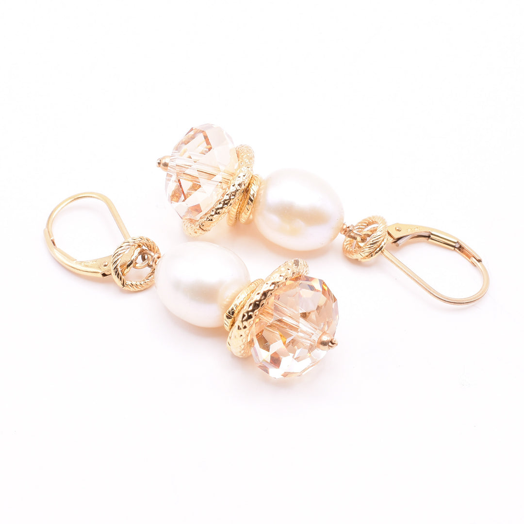 Cream Pearl and Swarovski Crystal Earrings handcrafted by artist Karley Smith. She has used freshwater pearls, Swarovski crystals in Golden Shadow and gold-plated wire and adornments to create them. Ear hooks are gold-filled. Each earring measures 1.60" x 0.50" including hook.