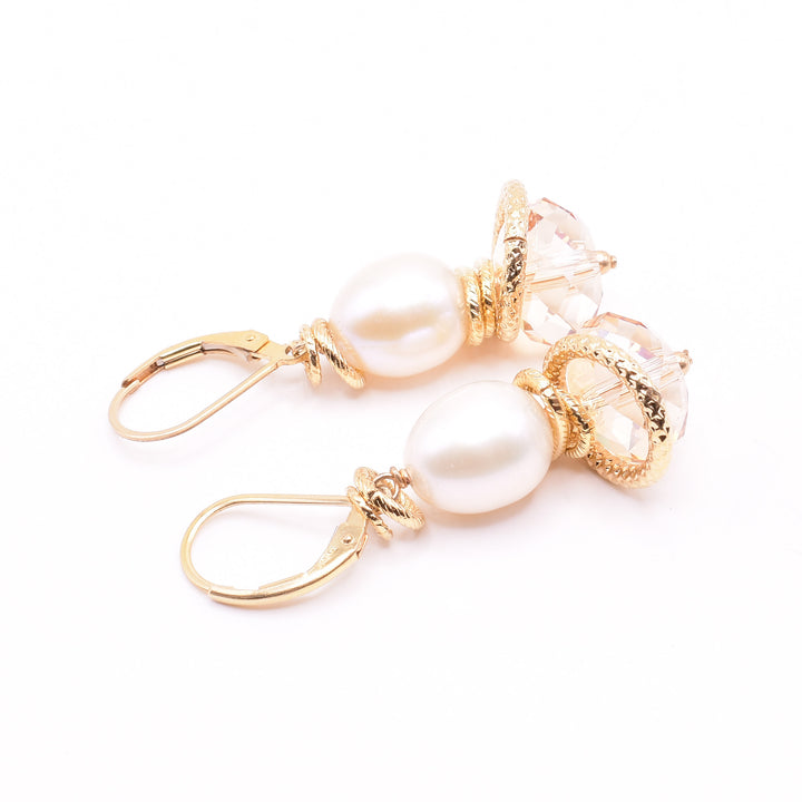 Cream Pearl and Swarovski Crystal Earrings handcrafted by artist Karley Smith. She has used freshwater pearls, Swarovski crystals in Golden Shadow and gold-plated wire and adornments to create them. Ear hooks are gold-filled. Each earring measures 1.60" x 0.50" including hook.