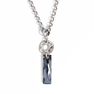 A queen's baguette cut dark grey Swarovski Crystal hangs below a flat, antique silver ring. Chunky, antique silver chain included. Pendant measures 1.88" x 0.50" including bail. 24" chain. By Karley Smith.