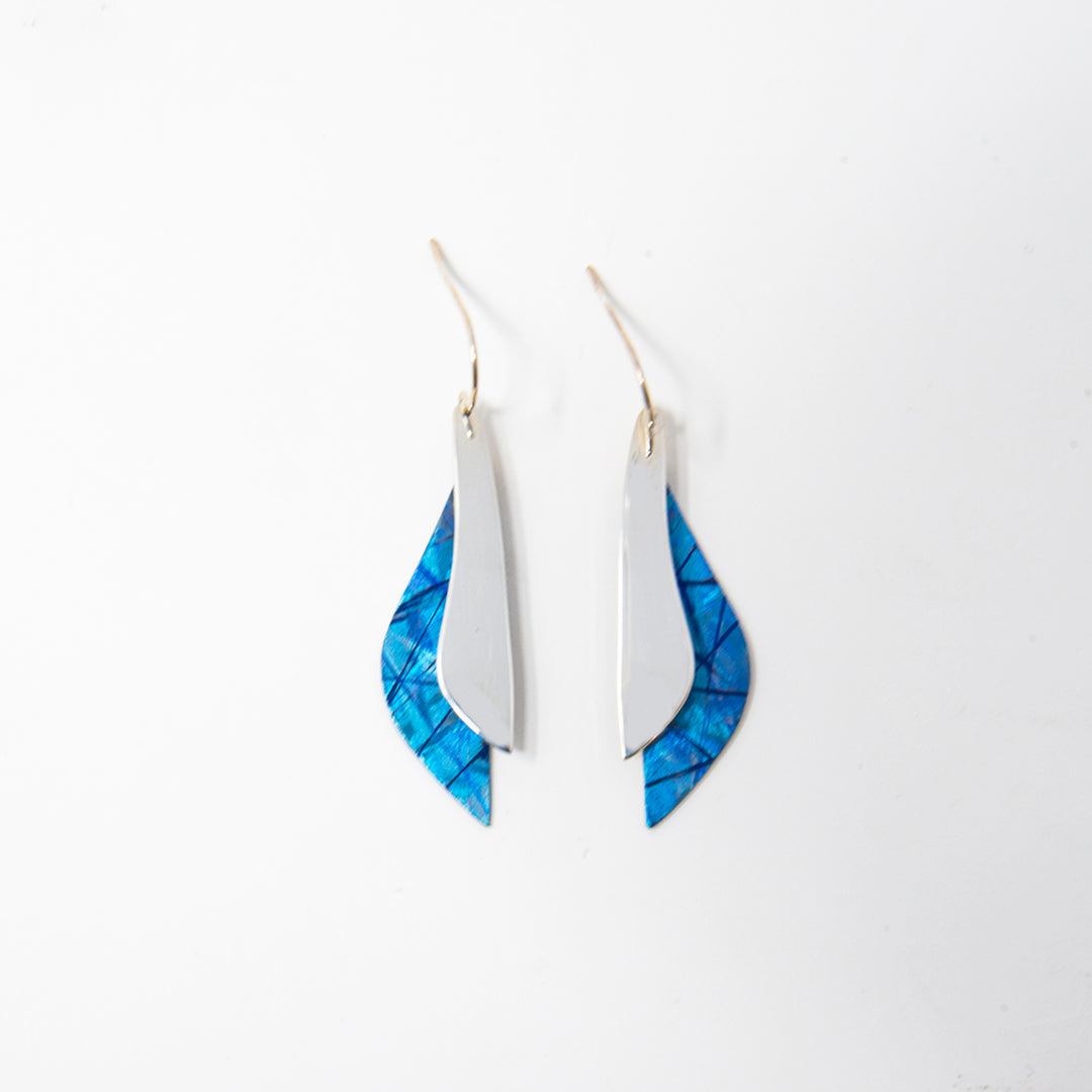 These titanium dangle earrings are made from sterling silver and anodized titanium and have a wavy, teardrop shape. The hangs are half anodized titanium with a blue color and other colorful designs on it and half shinning sterling silver.