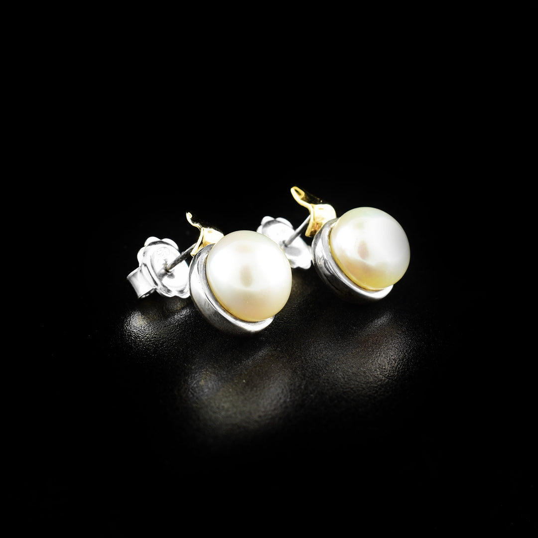 These pearl stud earrings are made from sterling silver, 14K gold and fresh water pearls. The earrings are silver and have gold highlights around the pearls.