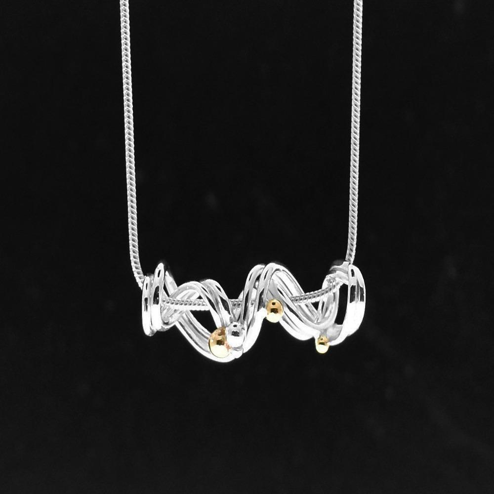 This coil necklace is made from sterling silver and 14K gold and has a coiled pendant. The interwoven wirework represents a continuous line of time. The gold and silver beads are the people, places and events that we encounter along the way. This design is to remind us of our resilience and strength as we carry on. 