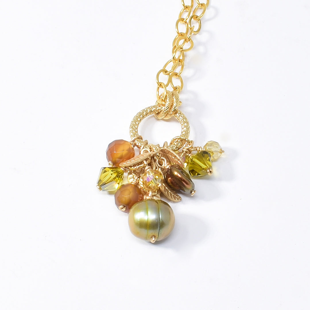gold leaf necklace handcrafted by artist Karley Smith. The pendant is made up of gold-plated wire and adornments, Swarovski Crystal, carnelian agate and freshwater pearl. Chain is gold-filled. Pendant measures 1.40" x 0.40" including bails and chain is 20" long.