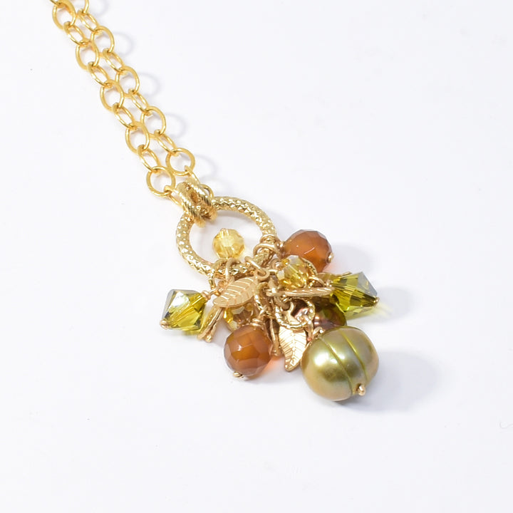 Golden Leaf Cluster Pendant Necklace handcrafted by artist Karley Smith. The pendant is made up of gold-plated wire and adornments, Swarovski Crystal, carnelian agate and freshwater pearl. Chain is gold-filled. Pendant measures 1.40" x 0.40" including bails and chain is 20" long.