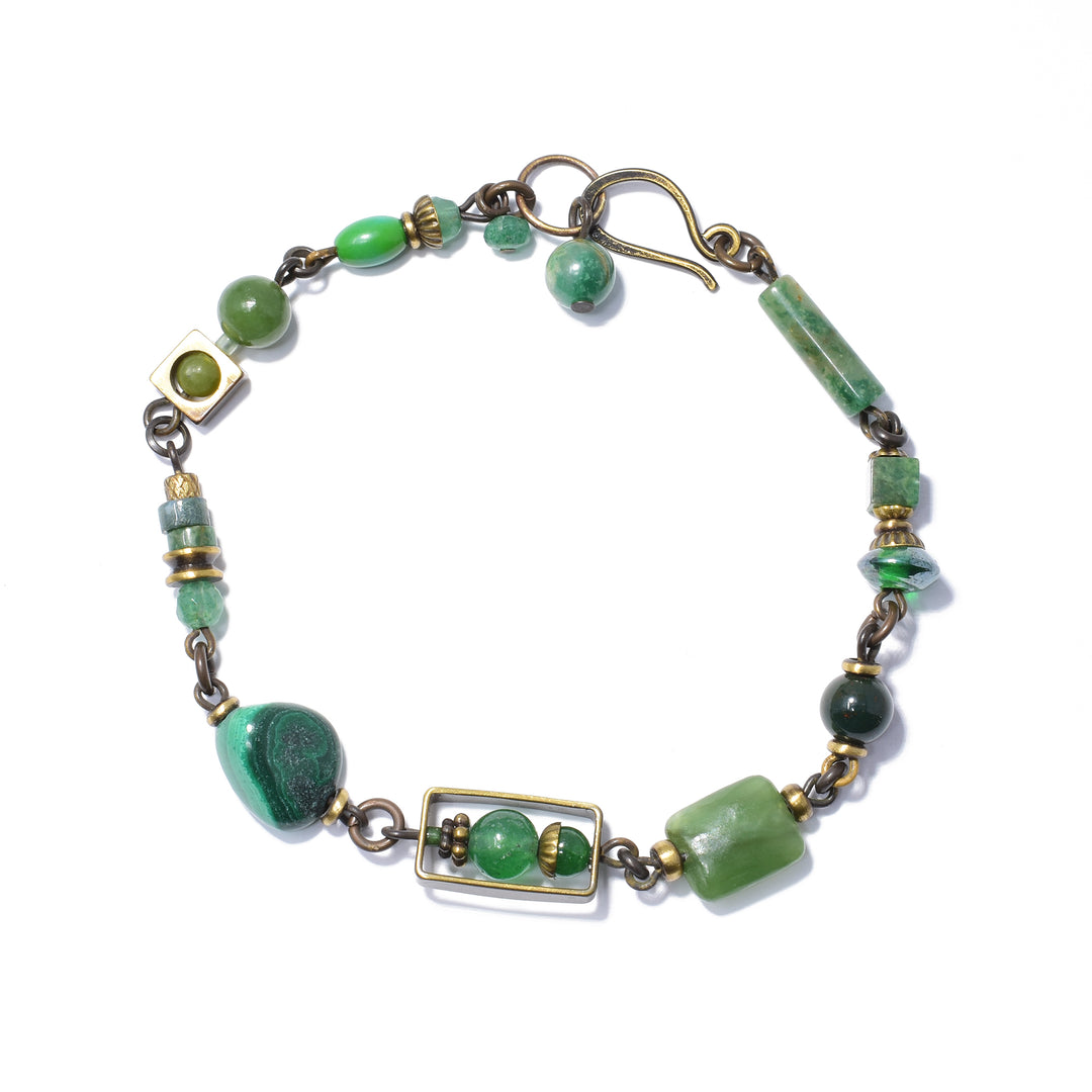 This unique beaded jade bracelet is made from handworked brass, aventurine, BC jade, malachite and magnesite. There are bead of different shapes, sizes and materials running along the entire piece. There are unique brass charms featured around the beads of this dainty bracelet.