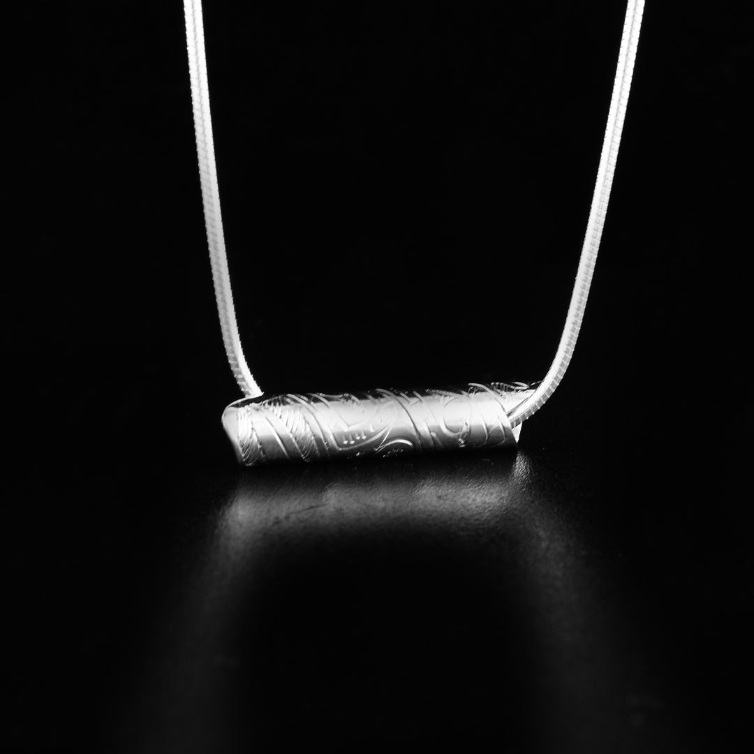 This unique Bear pendant is made from sterling silver and has a single thin band coiled into a cylinder. There is a depiction of the Bear carved into the surface of this spiral pendant.