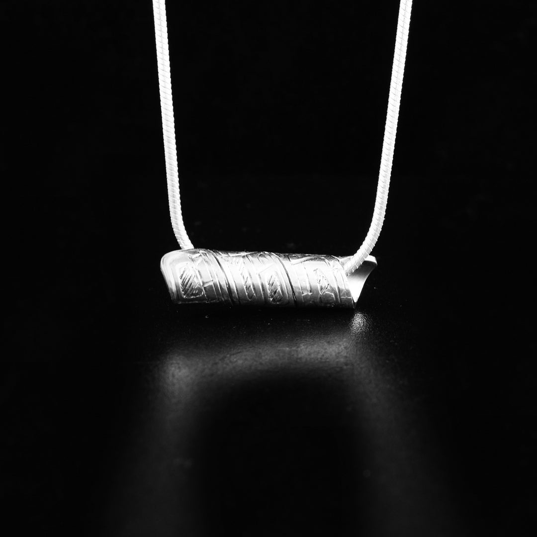 This Hummingbird pendant is made form sterling silver and has a band that has been twisted into a coiled cylinder. There is a depiction of the Hummingbird carved into the surface of the band.