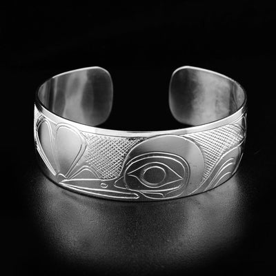 This Hummingbird bracelet depicts the head of the hummingbird drinking from a flower in the center. To the right is the bird's wings and body. The background is cross-hatched.