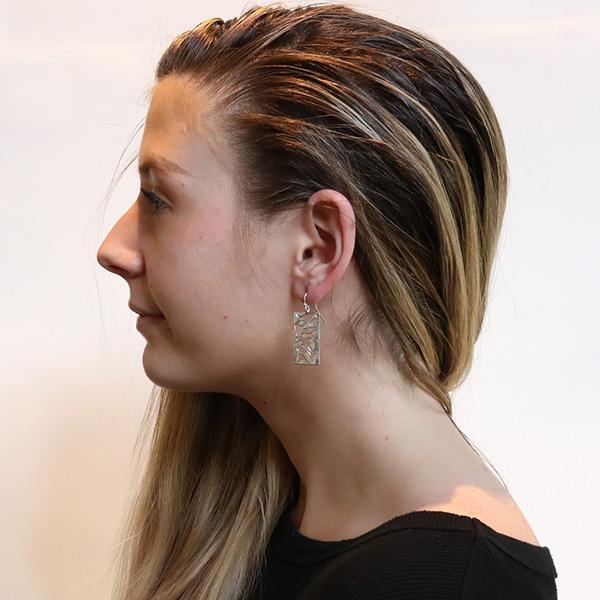 These dangling Wolf earrings are made from sterling silver and has large, rectangular hangs. There are cutout designs on the hangs that depict the Wolf.