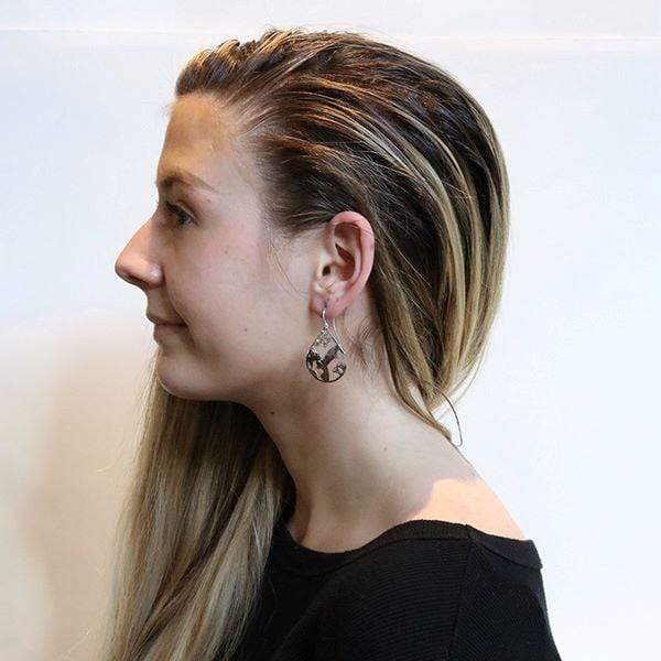 These sterling silver dangle earrings have teardrop shaped hangs with cutout designs that depict the Hummingbird.