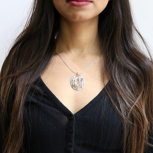 This silver and gold Frog pendant is made from sterling silver and 18K gold. The pendant is oval shaped and has cutout designs that depict the Frog. The eyes of the frog are made from 18K gold.