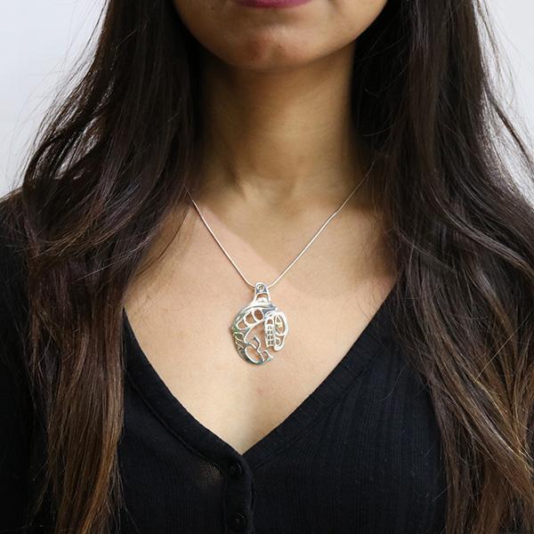 This beautiful Orca pendant is made form sterling silver and 18K gold and is shaped like the Orca at the peak of its leap out of the water. There are cutout designs in the pendant that depict the Orca and the eye of the Orca is made from gold.