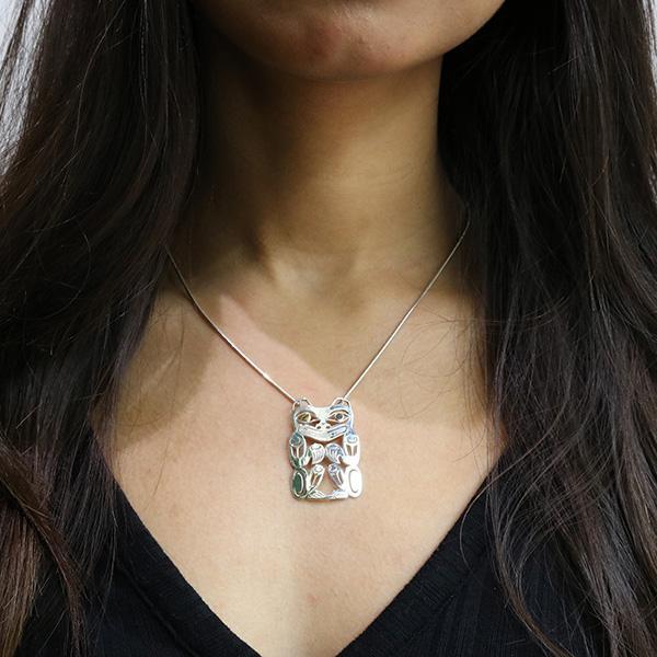 This cutout Bear pendant is made from sterling silver and 18k gold and is shaped like the Bear. There are cutout designs on the surface of it that depict the Bear and the eyes of it are made from gold.