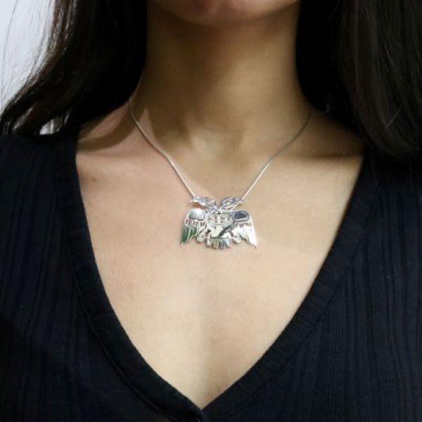 This unique, cutout Eagle pendant is made from sterling silver and 18K gold. The piece is shaped like and has intricate, cutout designs depicting the Eagle legend with two heads. There are gold embellishments featured on the piece including the eyes of the Eagle.