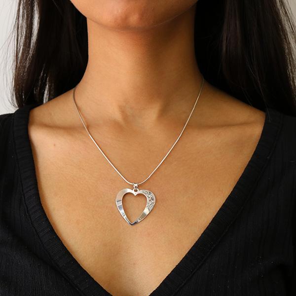These sterling silver heart pendant necklace has a heart shaped cutout in the middle of it. There are cutout designs in the surface of the pendant that depicts the Eagle and its eye is made from 18K gold.