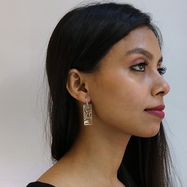 These dangling Raven earrings are made from sterling silver and have rectangle hangs. There are cutout designs that depict the Raven cast into the hangs.