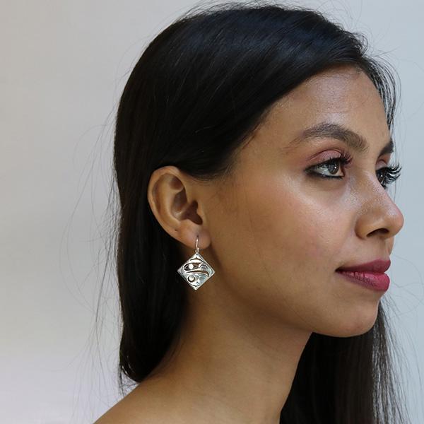 These dangling, diamond shaped earrings are made from sterling silver and have cutout designs on the hangs that depict the Eagle.