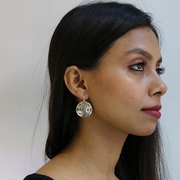 These dangling Moon earrings are made from sterling silver and have circle shaped hangs. There are cutout designs on the hangs that depict the Moon.