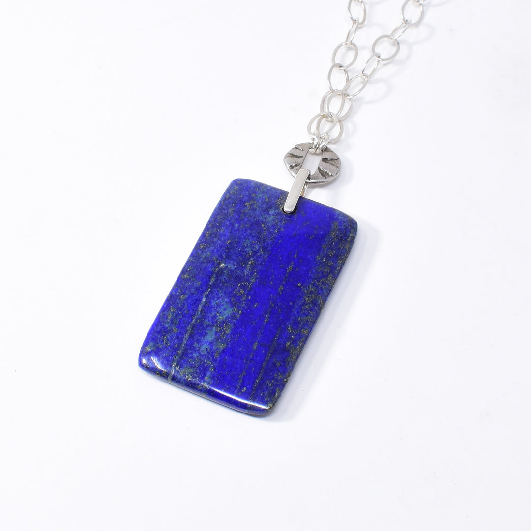 This genuine lapis lazuli necklace with pendant has an antique silver chain and the large, rectangle pendant made from the gem is held using sterling silver. 