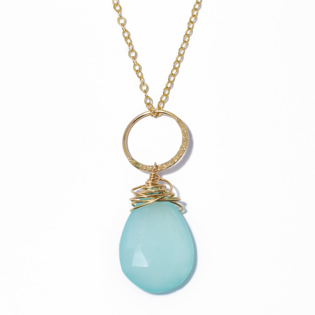 Dazzling Light Blue Chalcedony Pendant with Ring Necklace handcrafted by artist Debra Nelson. She has used light blue chalcedony, 14K gold fill wire and a 14K gold fill ring to create the pendant. Half of ring is hammered. 14K gold fill chain included. Pendant measures 1.56" x 0.63" including ring. Chain is 15.75" long with 2.25" extender.