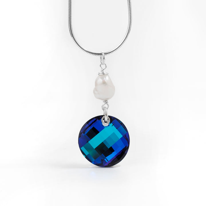 Dazzling Medium Bermuda Blue Twist Pendant with Pearl handcrafted by artist Debra Nelson. Made of sterling silver, Bermuda Blue Swarovski Crystal and freshwater pearl. Pendant measures 1.50" x 0.69" including bail. Chain not included.