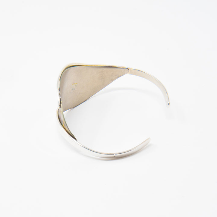 This unique titanium bracelet cuff is made from sterling silver and anodized titanium. This piece has a wide titanium section that is held between thin, silver bands; the bands extend past the wide section and leave a gap in the back of it. There are brilliant colors and designs on the surface of the titanium achieved by anodizing the metal.