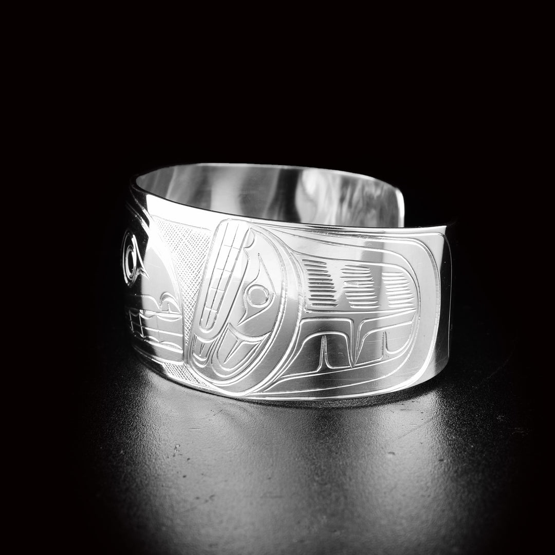 This sterling silver cuff bracelet has a wide, tapered band with a depiction of the Orca carved into the surface of it.