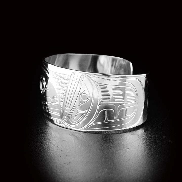 This sterling silver cuff bracelet has a wide, tapered band with a depiction of the Orca carved into the surface of it.