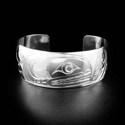 Orca cuff bracelet hand-carved by Indigenous artist Travis Henry. Made of sterling silver. Bracelet is 6.19" long with 0.94" gap and has width of 1". Ends taper down to 0.75".